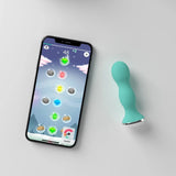A smartphone showing a colorful puzzle game sits beside the turquoise Perifit Kegel Exerciser – Smart Pelvic Floor Trainer by Perifit on a light gray surface.
