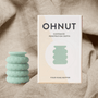 Ohnut depth limiting rings next to a box resting on a sheet representing the bedroom - to reduce pain with sex