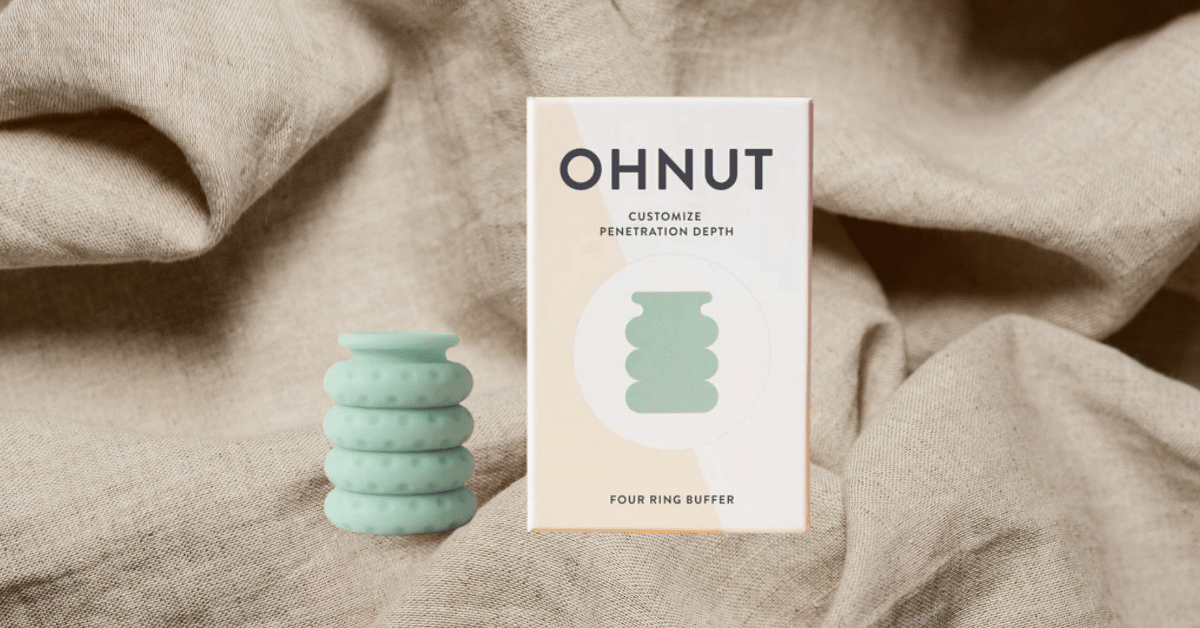Ohnut depth limiting rings next to a box resting on a sheet representing the bedroom - to reduce pain with sex