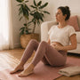 Woman sitting on a yoga mat at home with a hand resting below her navel, breathing through a diastasis recti exercise