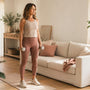 Woman standing tall on a yoga mat at home holding light dumbbells, strength training with a prolapse
