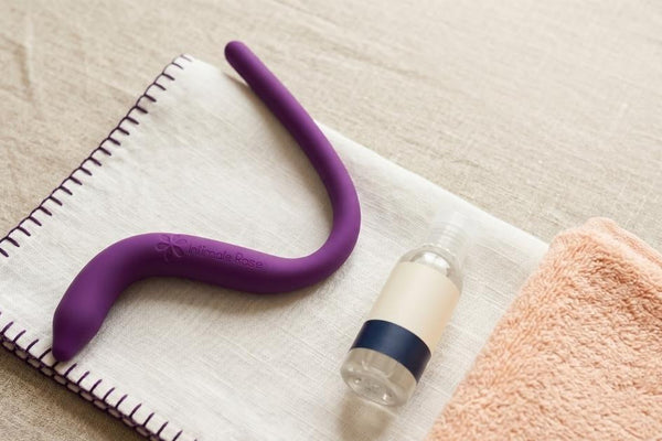 Intimate Rose pelvic wand on a folded cloth beside water-based lubricant, set up for at-home pelvic floor release
