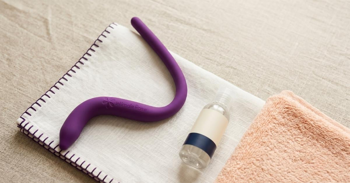 Intimate Rose pelvic wand on a folded cloth beside water-based lubricant, set up for at-home pelvic floor release
