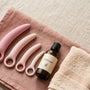 Graduated set of silicone vaginal dilators arranged small to large on linen beside lubricant and a towel for at-home use