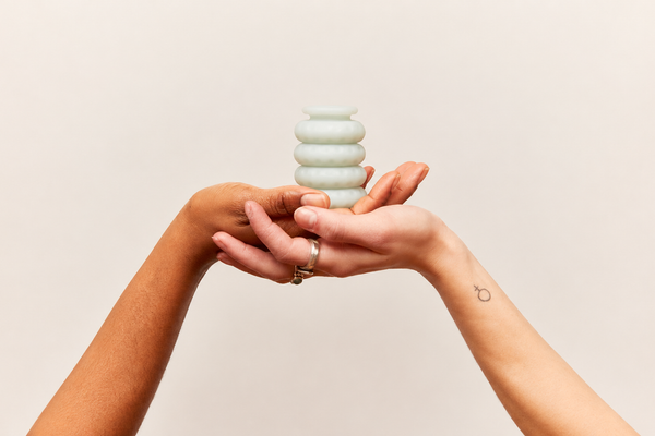 Stack of soft silicone Ohnut buffer rings held in two cupped hands against a warm neutral background