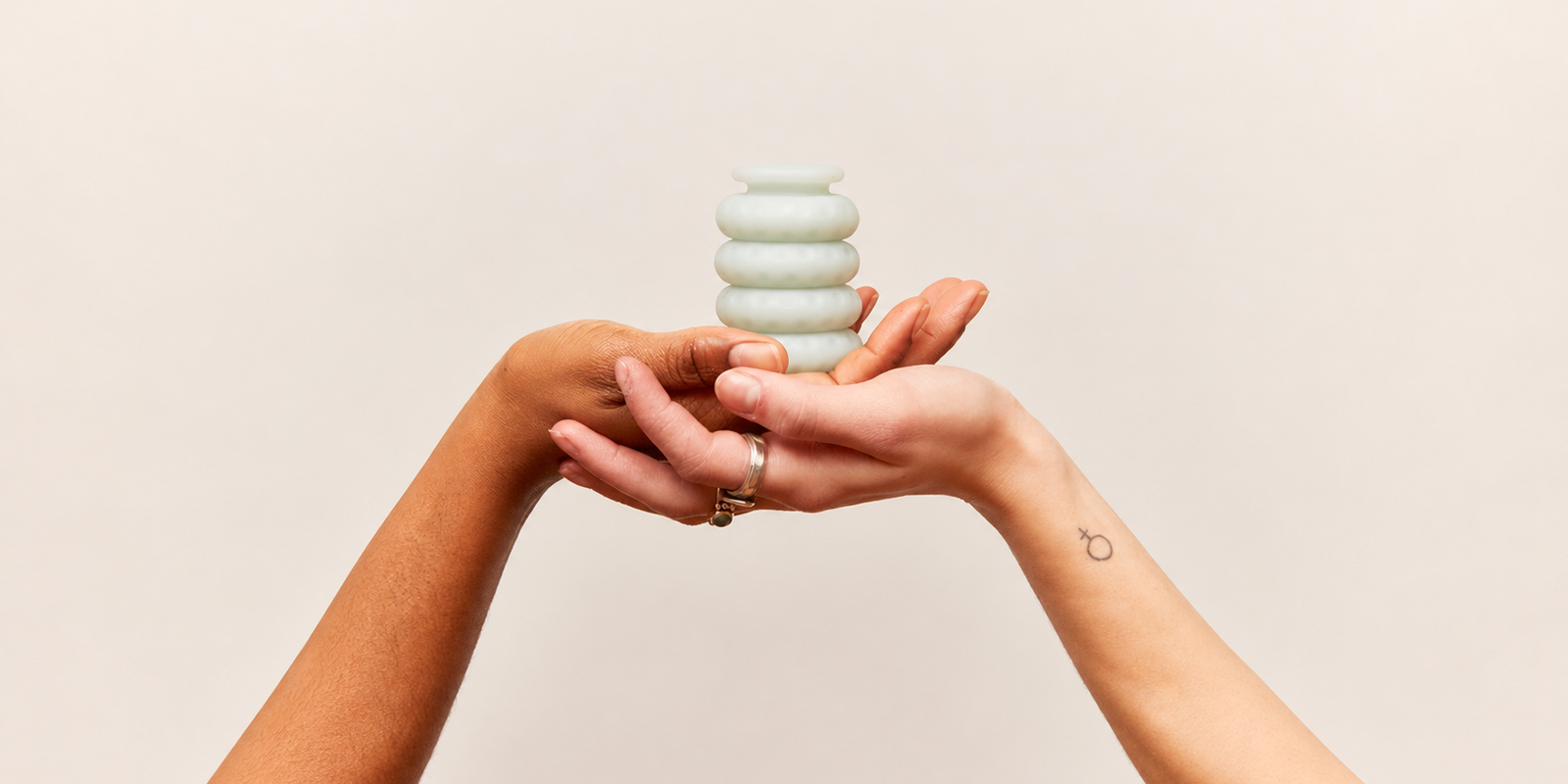 Stack of soft silicone Ohnut buffer rings held in two cupped hands against a warm neutral background