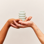 Stack of soft silicone Ohnut buffer rings held in two cupped hands against a warm neutral background