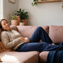 Australian woman reclining calmly on a linen sofa at home, eyes closed and shoulders relaxed, easing pelvic floor tension