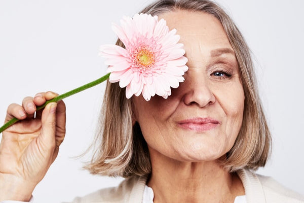 A lady going through the signs of menopause holding a flower.