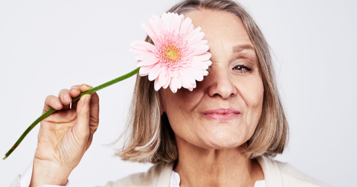 A lady going through the signs of menopause holding a flower.
