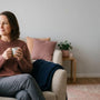 Woman relaxing calmly at home with a cup of tea, representing living well with overactive bladder symptoms
