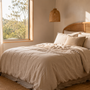 Calm, softly lit Australian bedroom with linen bedding, a glass of water and a folded towel on a wooden bedside table, a private and unhurried at-home setting for men's pelvic health