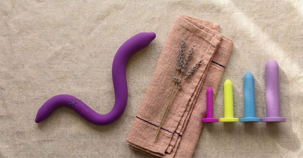 Intimate Rose pelvic wand beside a graduated set of coloured vaginal dilators on linen, comparing the two pelvic floor tools