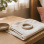 Small silicone ring pessary resting on folded linen beside a ceramic dish and eucalyptus on a timber bedside table