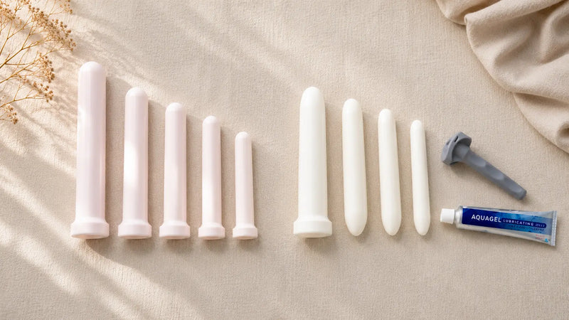 Amielle Comfort and Amielle Care vaginal dilator sets compared side by side — graduated tapered and non-tapered plastic dilators with universal locking handle and Aquagel lubricant on cream linen.