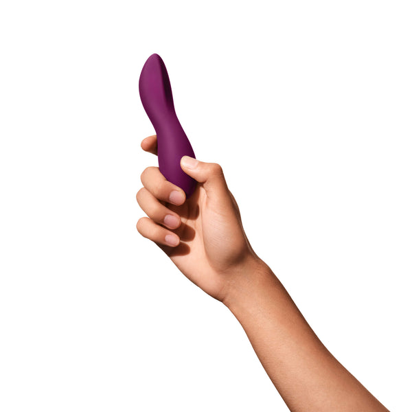 A hand presents the Dame Dip 2.0 - Basic Vibrator, a purple curved device by Dame, crafted from medical-grade silicone, set against a plain white background. This massager boasts a sleek design for effective clitoral stimulation.