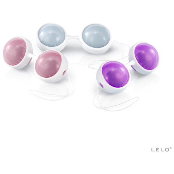 The LELO Beads Plus Pleasure Set by LELO features four round, smooth Ben Wa balls in pastel pink, purple, and light blue with white holders and retrieval strings, displayed on a white background. The LELO logo is at the bottom right corner.