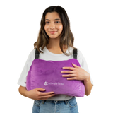 A person smiling while holding a large, purple Post-Surgery Mastectomy Pillow featuring the 