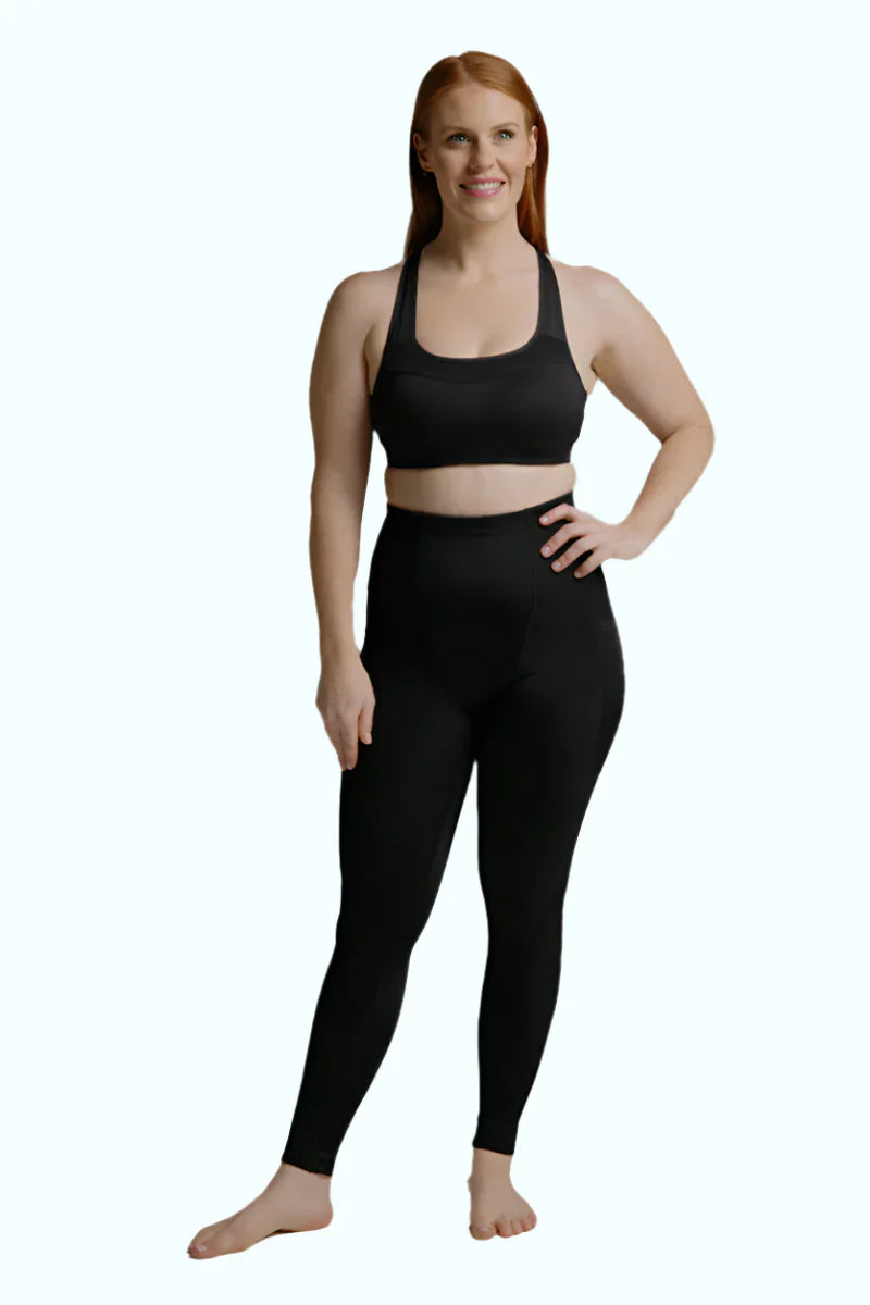 Woman wearing black SRC Restore full-length compression leggings, front view