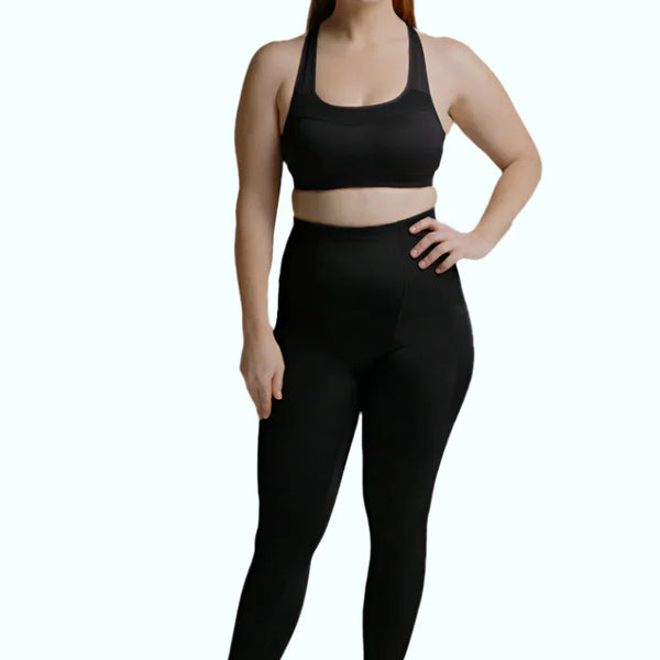 Woman wearing black SRC Restore full-length compression leggings, front view