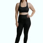 Woman wearing black SRC Restore full-length compression leggings, front view