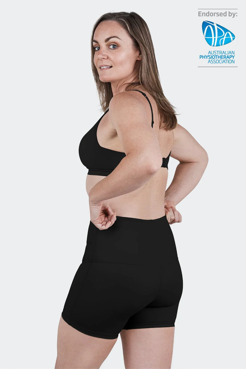Woman wearing black SRC Restore Mini compression shorts, front view