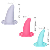 The She-ology™ 3-piece Wearable Vaginal Dilator Set by Calexotics includes an image of three differently colored, body-safe silicone objects shaped like small cones with flat circular bases. These silicone objects are grey, pink, and teal and come with measurements for their height and width in both inches and centimeters. This set is specifically designed for vaginal dilation.