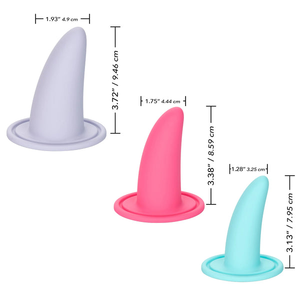 The She-ology™ 3-piece Wearable Vaginal Dilator Set by Calexotics includes an image of three differently colored, body-safe silicone objects shaped like small cones with flat circular bases. These silicone objects are grey, pink, and teal and come with measurements for their height and width in both inches and centimeters. This set is specifically designed for vaginal dilation.