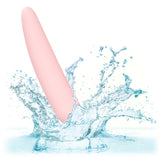 A pink, cylindrical piece from the Calexotics Inspire Silicone Dilator Kit is partially submerged in water, splashing against a white background.