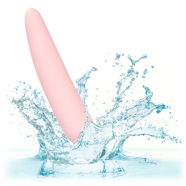 A pink, cylindrical piece from the Calexotics Inspire Silicone Dilator Kit is partially submerged in water, splashing against a white background.