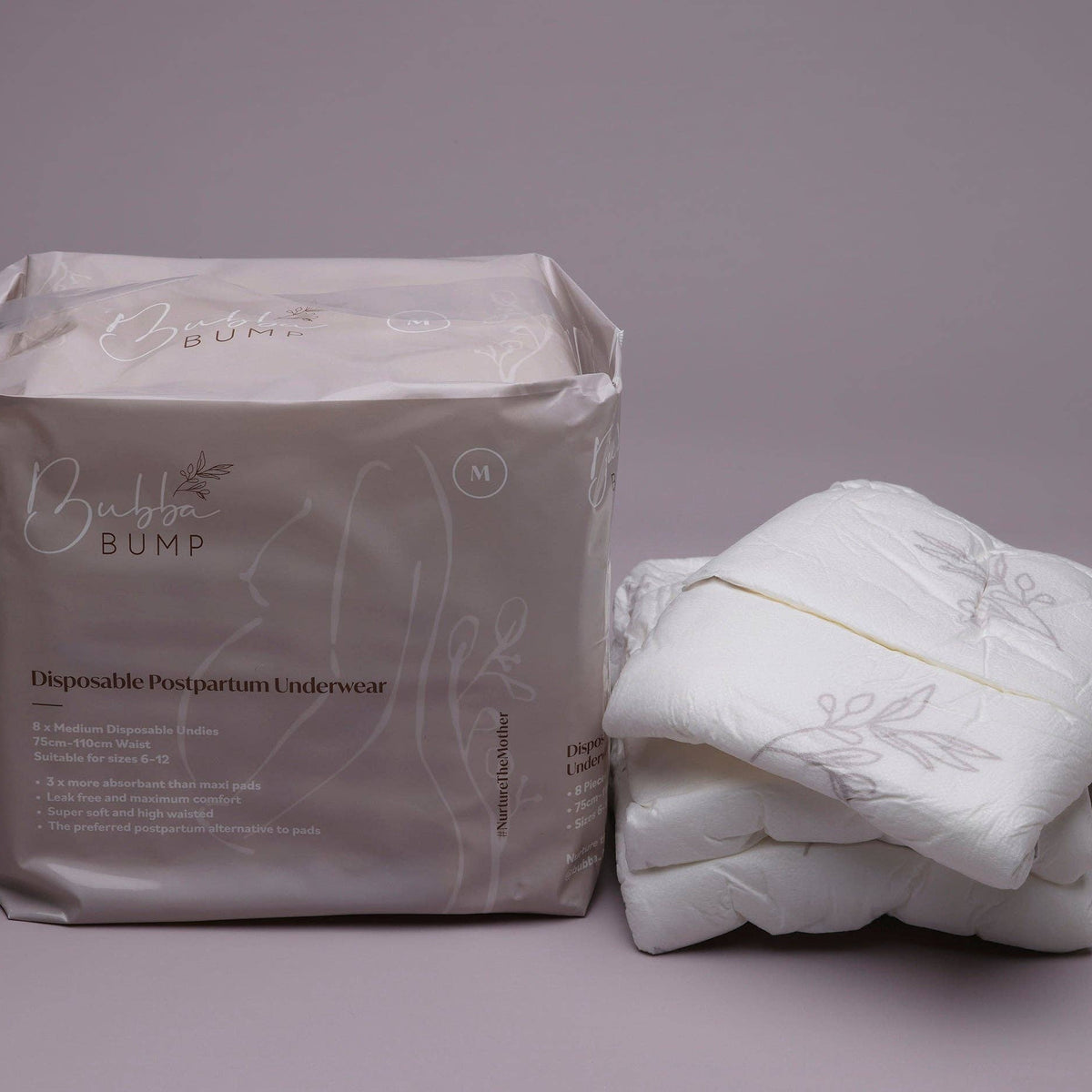 A package of Bubba Bump Disposable Postpartum Underwear in size M showcases dependable leak-proof protection. Next to it is a stack of folded white underwear featuring a floral design on a neutral gray background.