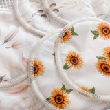 There are three sets of Bubba Bump Organic Bamboo Reusable Breast Pads - 14 Pack. One set displays a white backdrop adorned with sunflowers, another set features a light pink and brown floral pattern, and the third set showcases airy leaves in pastel pink and beige tones. These ultra-absorbent breast pads are stitched around the edges for enhanced durability.