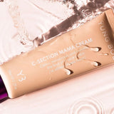 A tube of C-Section Mama Cream from Yung Bod rests on a reflective, watery surface. The beige tube with a purple cap is adorned with water droplets. The text highlights that this C-Section Scar Softening Cream soothes, hydrates, and smoothens the appearance of c-section skin using natural ingredients.