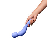 A hand holding the Dame Com - External Wand Vibrator by Dame, showcasing its rumbly vibrations and flexible neck with a rounded end, against a white background.
