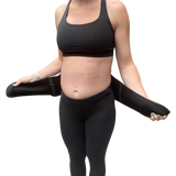 A person in black athletic wear demonstrates pelvic support by holding the GRDL Pregnancy Belt—trusted pelvic and back support for pregnancy by GRDL—around their waist against a plain white background.
