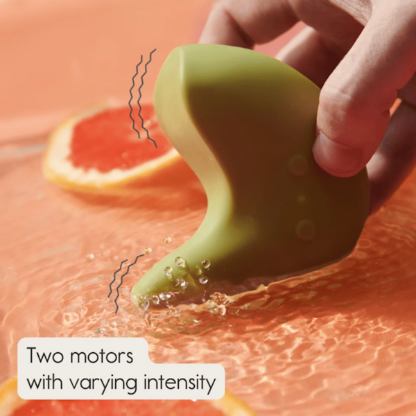 A green, curvy Kiwi Vibrating Pelvic Massager by The Pelvic People is held above liquid with two grapefruit slices. Text reads, "Two motors with varying intensity for pelvic floor tightness relief.