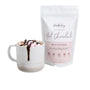 A white mug of hot chocolate with marshmallows and drizzle sits next to The Breastfeeding Tea Co’s “Lactation Hot Chocolate with Collagen” pouch—a delicious, dairy-free treat for lactation support.