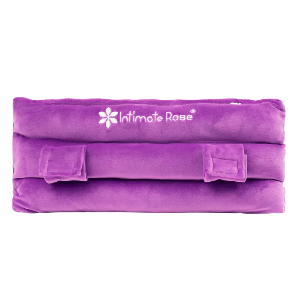 The Intimate Rose Post-Surgery Seat Belt Pillow in purple is designed for ultimate comfort and post-surgery pain relief. It features soft, plush fabric and adjustable velcro straps, making it an ideal support option as a mastectomy pillow alternative. The fabric proudly displays the brand logo.