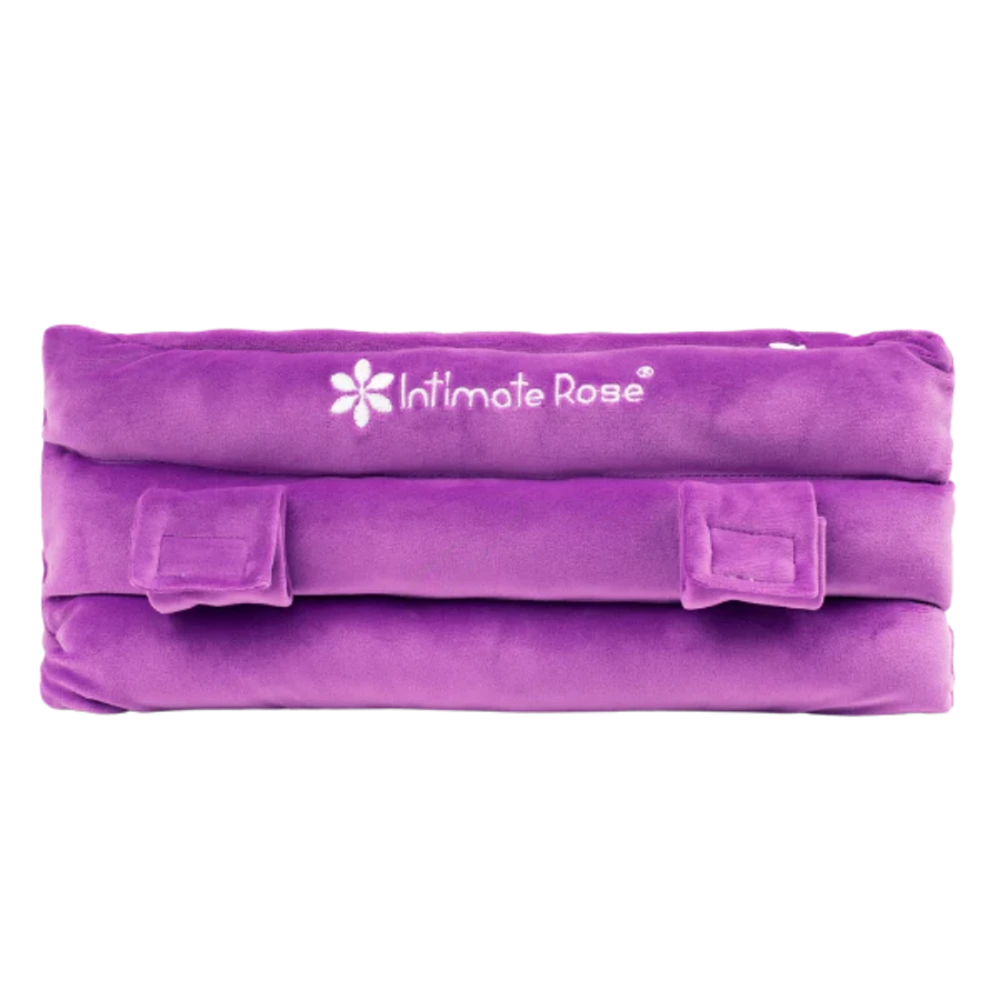 The Intimate Rose Post-Surgery Seat Belt Pillow in purple is designed for ultimate comfort and post-surgery pain relief. It features soft, plush fabric and adjustable velcro straps, making it an ideal support option as a mastectomy pillow alternative. The fabric proudly displays the brand logo.