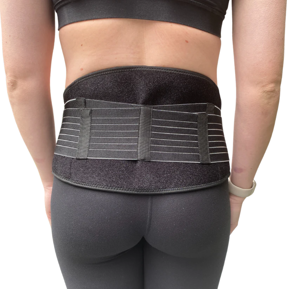A person wearing black athletic clothing and the GRDL Pregnancy Belt by GRDL, shown from behind with the belt fastened around the lower back and waist for trusted pelvic and back support during pregnancy.