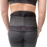 A person wearing black athletic clothing and the GRDL Pregnancy Belt by GRDL, shown from behind with the belt fastened around the lower back and waist for trusted pelvic and back support during pregnancy.