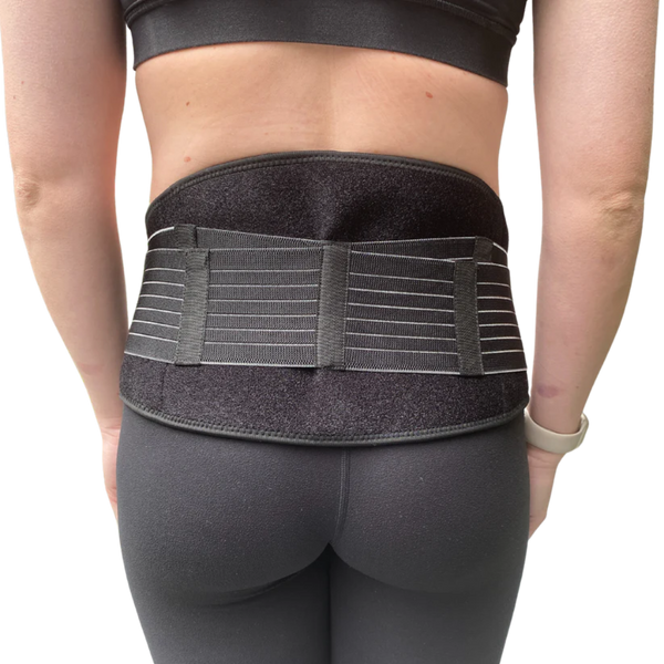 A person wearing black athletic clothing and the GRDL Pregnancy Belt by GRDL, shown from behind with the belt fastened around the lower back and waist for trusted pelvic and back support during pregnancy.