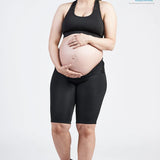 A pregnant woman stands, smiling at the camera while wearing a black sports bra and the SRC Maternity Shorts by SRC Health. She cradles her baby bump with both hands. The image is endorsed by the Australian Physiotherapy Association, whose logo appears in the top right corner.