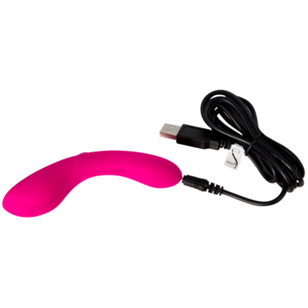 The Mini Swan Wand, a bright pink curved G spot vibrator with a smooth surface, lies next to a black USB charging cable.