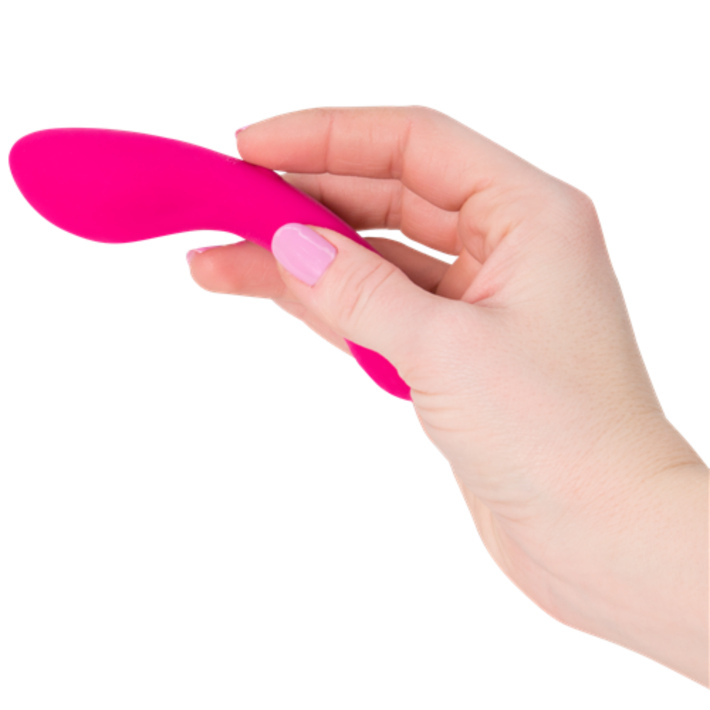 A hand with pink nail polish is holding a small, pink The Mini Swan Wand by Swan against a white background.