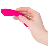 A hand with pink nail polish is holding a small, pink The Mini Swan Wand by Swan against a white background.