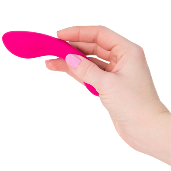 A hand with pink nail polish is holding a small, pink The Mini Swan Wand by Swan against a white background.