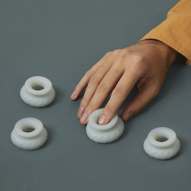 Hand pressing down on a soft white Ohnut depth-limiting buffer ring to show the squishy polymer texture — the four-ring set sets penetration depth during sex. Sold in Australia by Blossom Pelvic Health, a physio-led pelvic store