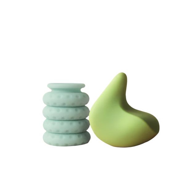 The Kiwi & Ohnut Starter Pack by The Pelvic People features a textured, mint green vase with a rounded shape alongside a smooth, sculptural green object on a beige surface against a warm orange background.