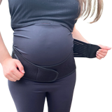 A pregnant woman adjusts the strap of a GRDL Pregnancy Belt by GRDL, worn over her clothes. The image focuses on her torso, highlighting trusted pelvic and back support for pregnancy.